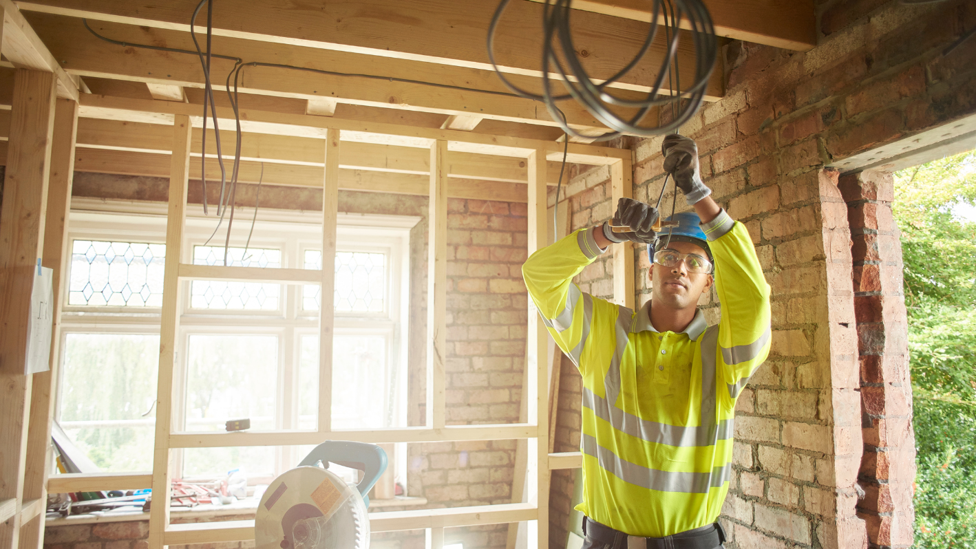 A man in a yellow shirt is holding a drill