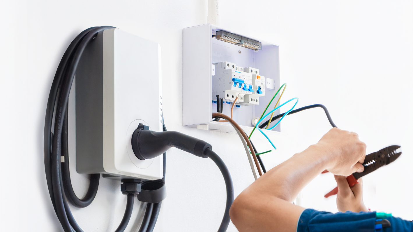 A person working on a wall mounted electrical device