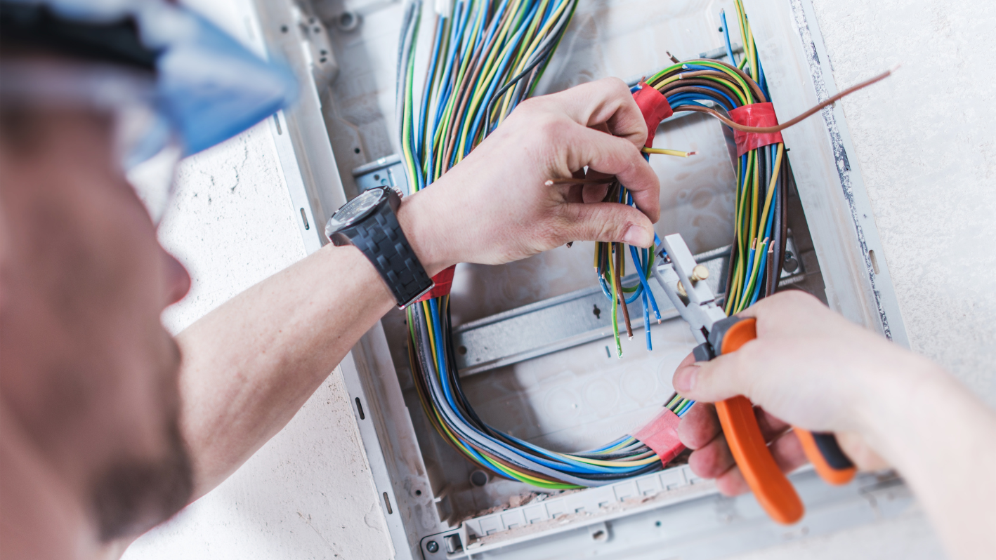 A man is working on a wiring box