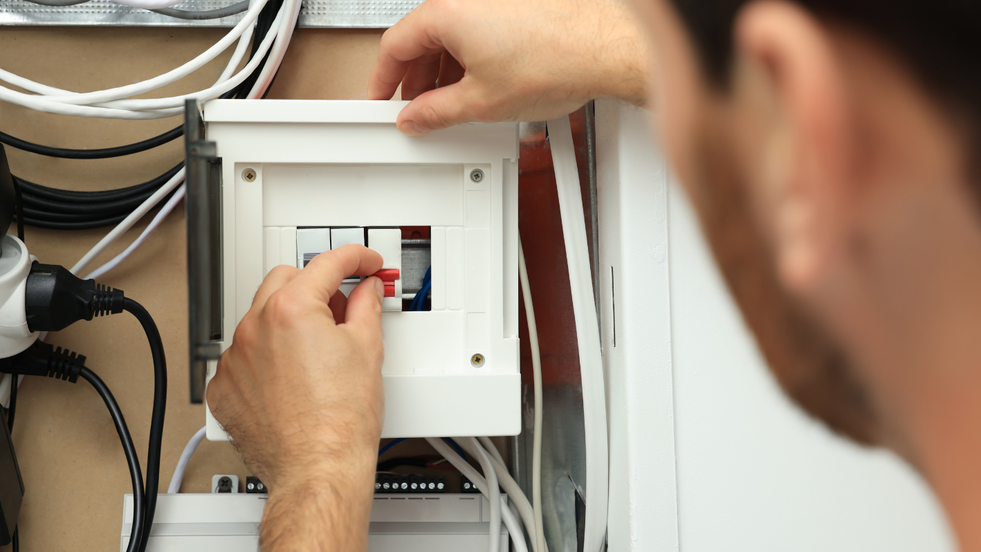 A man is working on an electrical panel